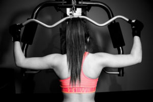 back of woman in pink bra lifting weights