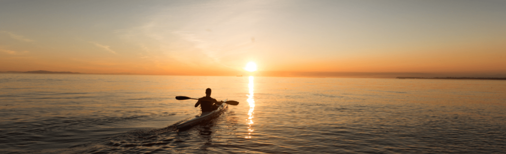person kayaks at sunset