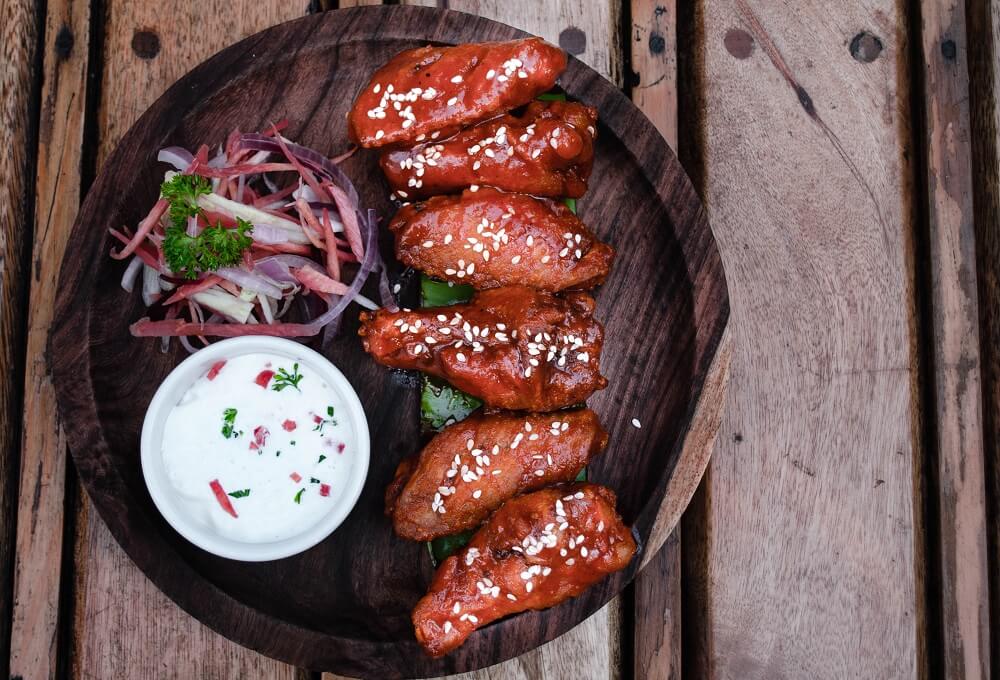 chicken wings on wooden plate with white dip and onions