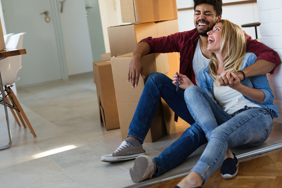 couple sitting on floor laughing next to cardboardboxes