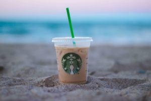 starbucks iced coffee in sand on beach