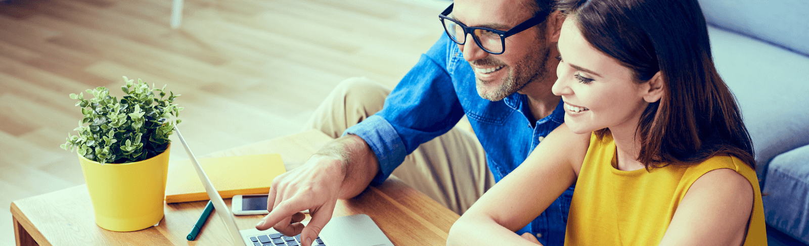 couple sits on floor in front of laptop on table